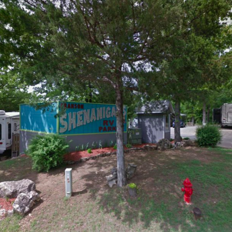 Camper walking a dog along a wooded path at Branson Shenanigans RV Park